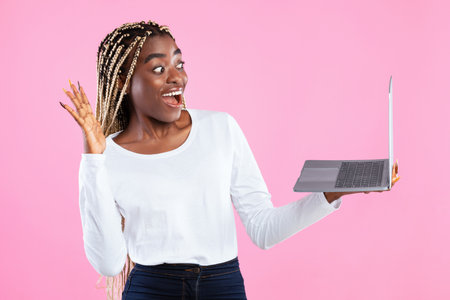 Black woman having videocall using laptop waving handの写真素材