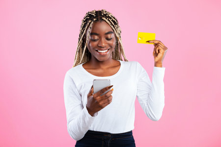 Young black woman holding credit card and smartphone
