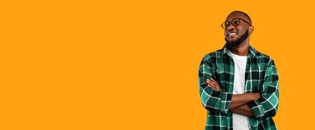 Black Man Posing Crossing Hands Looking Aside On Yellow Backgroundの写真素材