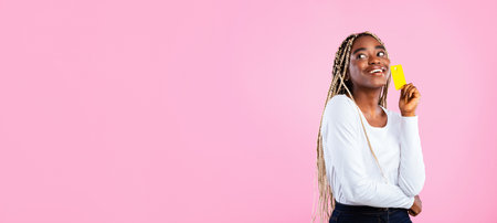 Excited African American woman with credit card looking at copy spaceの写真素材