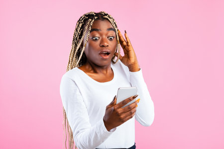 Shocked African American woman looking at smartphoneの写真素材