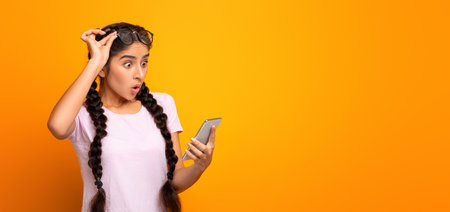 Excited indian woman using mobile phone, celebrating online winの写真素材