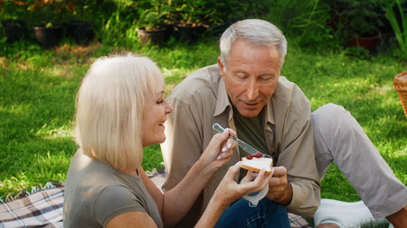 Couple enjoying outdoor dessert in a lush garden on a sunny afternoonの写真素材