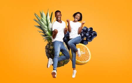 Happy couple enjoying tropical fruits on a bright orange backgroundの写真素材