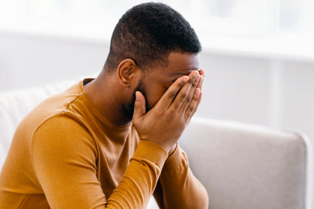 Desperate African Man Covering Face Crying Having Depression At Homeの写真素材