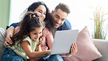 Happy Middle Eastern Family Of Three Spending Time With Laptop At Homeの写真素材