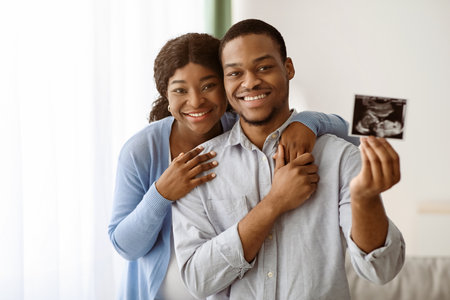 Attractive african american couple posing with baby sonogramの写真素材