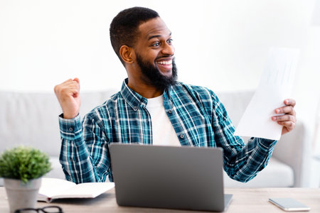Joyful Black Businessman Shaking Fists Holding Papers In Officeの写真素材