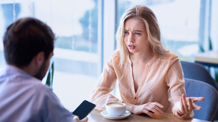 Gadget addiction. Upset millennial lady trying to talk to her boyfriend stuck in smartphone at city cafeの写真素材