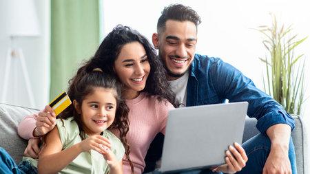 Middle Eastern Family Of Three With Laptop And Credit Card At Homeの写真素材