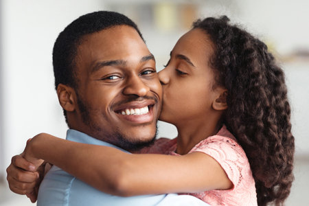 Cute black girl kissing her smiling father, closeupの写真素材