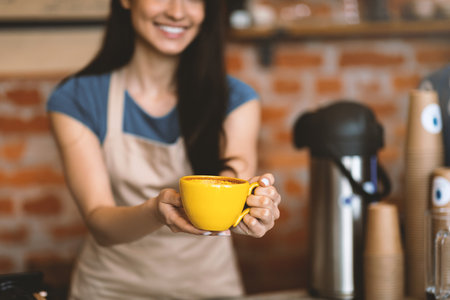 Unrecognizable barista welcoming guests at coffee house counter, offering cup of hot beverage, closeup, cropの写真素材