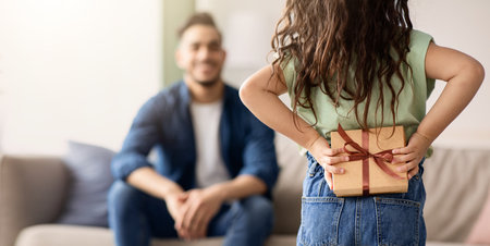 Little girl greeting her dad with Fathers Day, holding gift behind backの写真素材