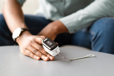 Black Man Measuring Oxygen Saturation Level With Pulse Oximeter Indoorsの写真素材