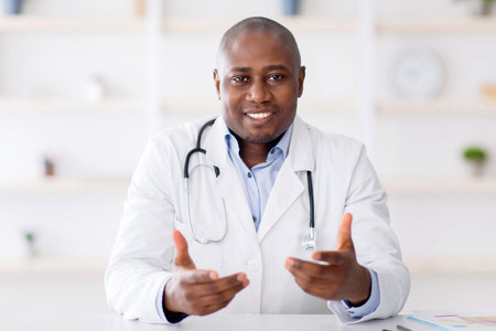 African american doctor sitting at workdesk at clinic, having appointments during coronavirus pandemicの写真素材
