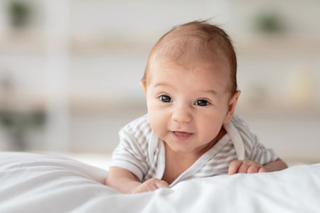 Closeup portrait of adorable newborn baby lying on his tummy on bedの写真素材
