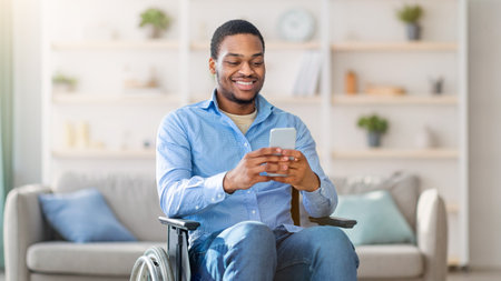 Black man in wheelchair using smartphone, browsing web or watching movie at homeの写真素材