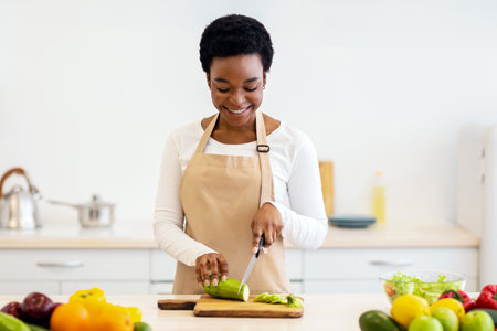 Positive African Lady Cutting Zucchini Cooking Vegetable Dish In Kitchenの写真素材