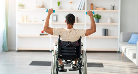 Back view of black guy in wheelchair exercising with dumbbells at home. Sports and disability conceptの写真素材