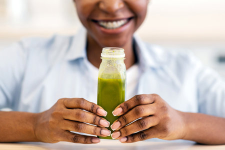 Unrecognizable Black Lady Posing With Green Smoothie Bottle Indoors, Cropped