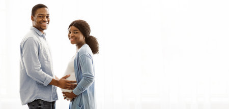 Loving expecting black couple posing over white backgroundの写真素材