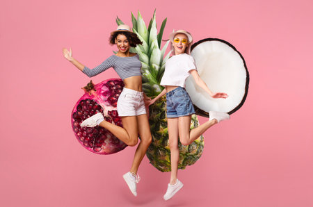 Joyful ladies jumping with fruit elements in colorful backgroundの写真素材