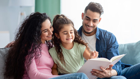 Happy Middle Eastern Family With Little Daughter Reading Book Togetherの写真素材