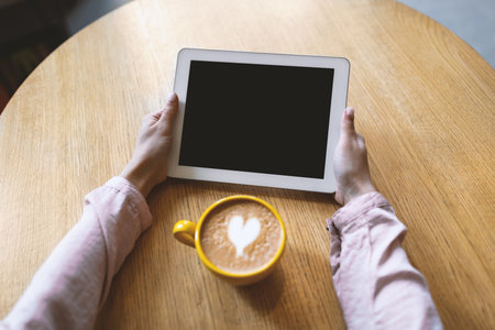 Breakfast at cafe. Unrecognizable lady holding tablet with empty blank screen at coffee break, mockup, closeupの写真素材