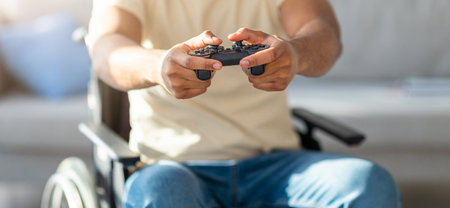 Cropped view of black guy in wheelchair enjoying online videogame, having fun at home, closeupの写真素材