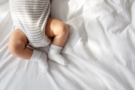 Top View Of Newborn Baby In Bodysuit And Socks Lying On Bedの写真素材