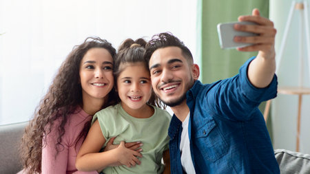 Happy Arab Family Of Three Taking Selfie With Smartphone At Homeの写真素材