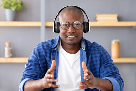 Mature african american freelancer man video calling and talking to camera, sitting at workplace in home ofiiceの写真素材