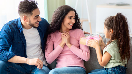 Adorable Little Girl Greeting Mom With Mothers Day, Giving Gift At Homeの写真素材