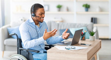 Black guy with headset communicating online on laptop, having business meeting from homeの写真素材