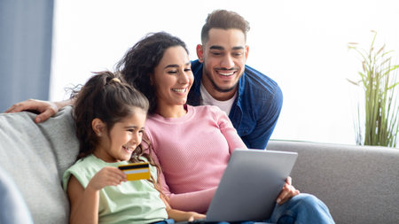 Happy Arabic Family Using Digital Tablet And Credit Card For Online Shoppingの写真素材