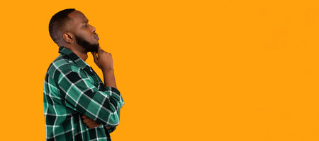 Side-View Portrait Of Thoughtful Black Man Looking Aside, Yellow Backgroundの写真素材