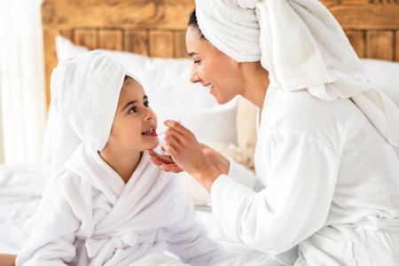 Mom putting make up on her cute little daughterの写真素材