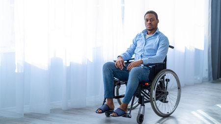 Depression in with disability patients. Portrait of black man in wheelchair having psychological problems at homeの写真素材