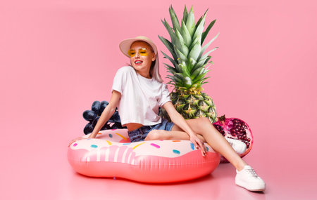 Young woman enjoys summer vibes with a colorful donut pool floatの写真素材