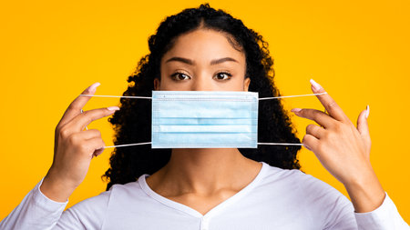 Protection Against Virus. Portrait Of Young Black Woman Holding Medical Face Mask