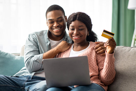 Happy african american couple with credit card and laptopの写真素材
