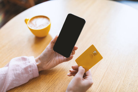Contactless payment during coronavirus quarantine. Woman holding cellphone and credit card, drinking...