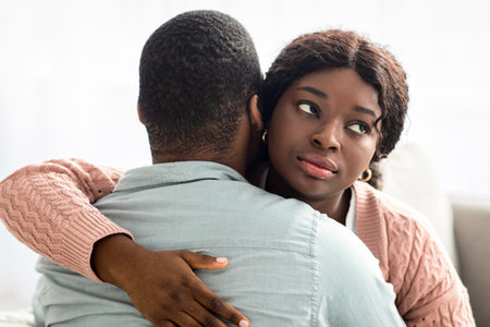 Indifferent black lady hugging her boyfriend or husbandの写真素材