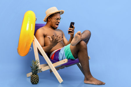 Frustrated black guy shouting at smartphone, feeling stressed, having bad internet connection on summer vacationの写真素材
