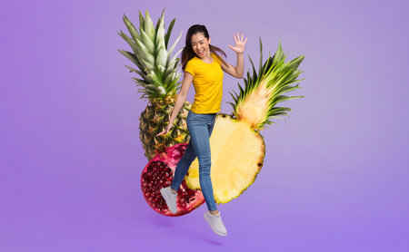Young woman joyfully jumping with vibrant fruits on a colorful backgroundの写真素材