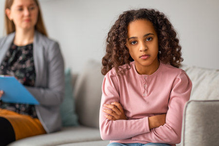 Psychological help and assistance. Sad teen girl sitting back to doctor, looking at cameraの写真素材