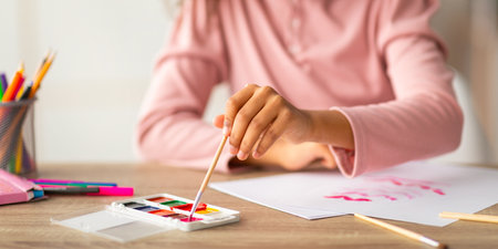 Art hobby. Black teen girl drawing on paper, mixing the colors on the palette during painting.