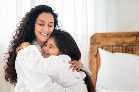 Loving mother and daughter in bathrobes embracingの写真素材