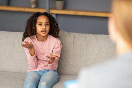 African american teen girl at psychologist office, talking about problems in family, teenage troubles, sitting on sofaの写真素材