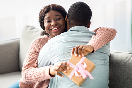 Happy african american lady with present hugging her loverの写真素材